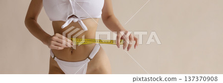 Sexy fitness diet concept with woman measuring slim waist with tape measure in white lingerie, weight loss and healthy body lifestyle 137370908