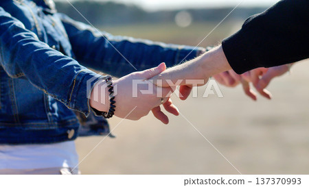 Couple holding hands with fingers interlocked, walking in trust and support Couple holding hands with fingers interlocked, walking in trust and support 137370993