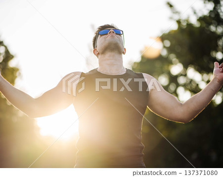 Man with outstretched arms feeling freedom and energy under summer sunbeams 137371080