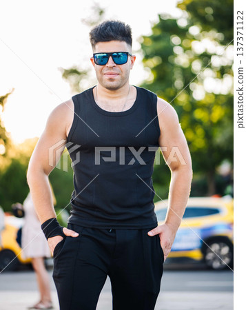Athletic man posing outdoors wearing black tank top and mirrored sunglasses Athletic man posing outdoors wearing black tank top and mirrored sunglasses 137371122