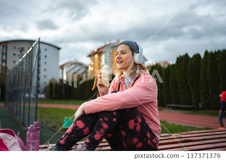 Woman eating banana after workout on running track Woman eating banana after workout on running track 137371376