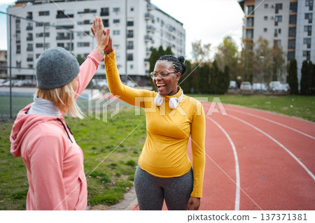 Diverse women giving high five on running track 137371381