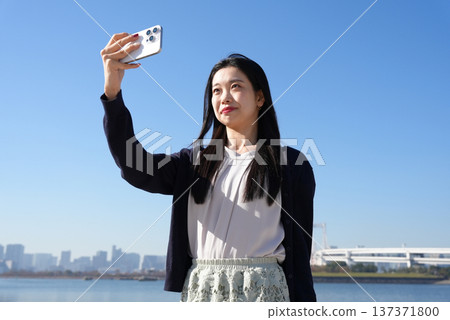 年輕女子在戶外看智能手機 年輕女子在戶外看智能手機 137371800