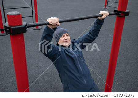 Adult Man Performing Pull-Up Exercise at Outdoor Gym. Training Outdoors Adult Man Performing Pull-Up Exercise at Outdoor Gym. Training Outdoors 137372375