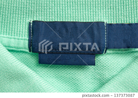 Blank blue laundry care clothes label on green shirt fabric texture background 137373087