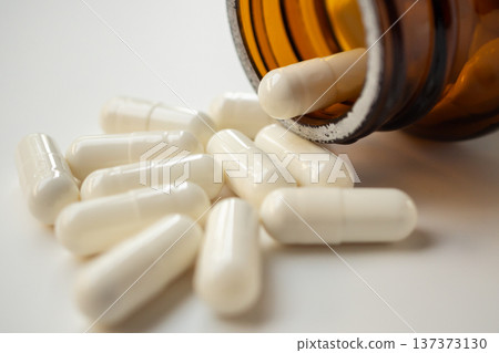 medicine pills capsule spilling out of bottle on white background medicine pills capsule spilling out of bottle on white background 137373130