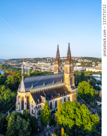 Beneath the clear sky, the Vysehrad Basilica of St. Peter and St. Paul stands majestically in Prague, bathed in warm morning light, revealing the beauty of its architecture and lush surroundings. Beneath the clear sky, the Vysehrad Basilica of St. Peter and St. Paul stands majestically in Prague, bathed in warm morning light, revealing the beauty of its architecture and lush surroundings. 137373712
