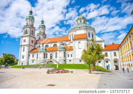 St. Lorenz Basilica showcases its stunning baroque architecture against a bright blue sky in Kempten. Visitors enjoy the peaceful surroundings and admire the historic structure during daytime. 137373717