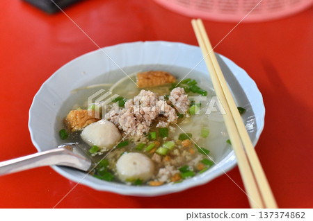 Noodle soup pork fish ball street food Asian cuisine hot bowl comforting noodle soup with pork fish ball and scallion red table 137374862