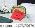 a red note leaning on a green bedside alarm clock 137375670
