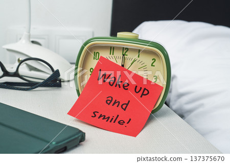 a red note leaning on a green bedside alarm clock 137375670