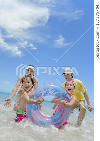 A family of four playing in the summer sea 137375704