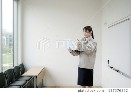 一位身穿工作服的女士正在訓練室講解 一位身穿工作服的女士正在訓練室講解 137376232