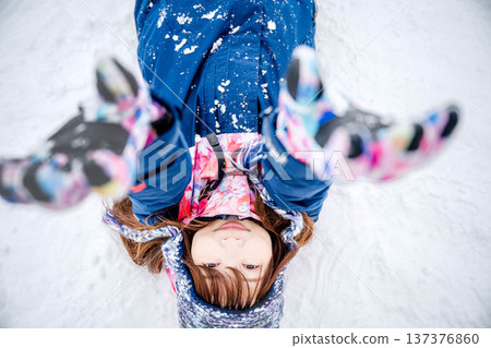 A young woman wearing ski wear playing with snow on the slopes 137376860