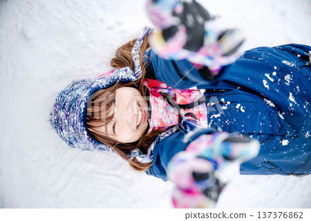一位身穿滑雪服的年輕女子在雪坡上玩雪。 137376862