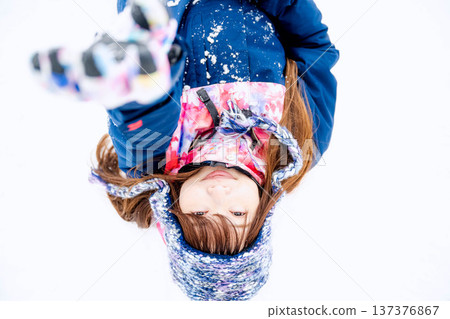 A young woman wearing ski wear playing with snow on the slopes A young woman wearing ski wear playing with snow on the slopes 137376867