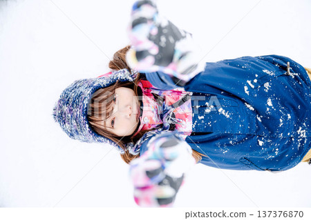 A young woman wearing ski wear playing with snow on the slopes A young woman wearing ski wear playing with snow on the slopes 137376870