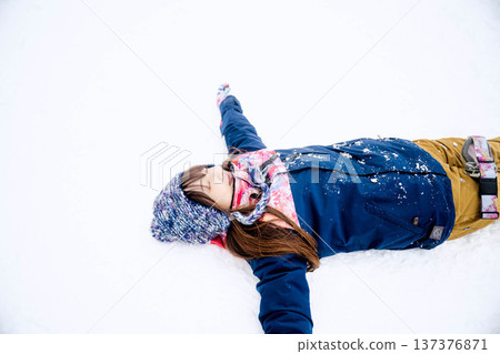A young woman wearing ski wear playing with snow on the slopes A young woman wearing ski wear playing with snow on the slopes 137376871