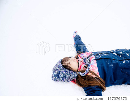 一位身穿滑雪服的年輕女子在雪坡上玩雪。 一位身穿滑雪服的年輕女子在雪坡上玩雪。 137376873