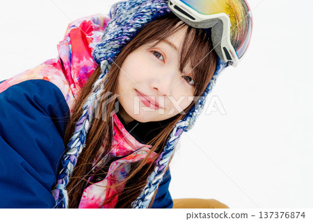 A young woman wearing ski wear playing with snow on the slopes A young woman wearing ski wear playing with snow on the slopes 137376874