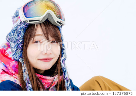A young woman wearing ski wear playing with snow on the slopes A young woman wearing ski wear playing with snow on the slopes 137376875