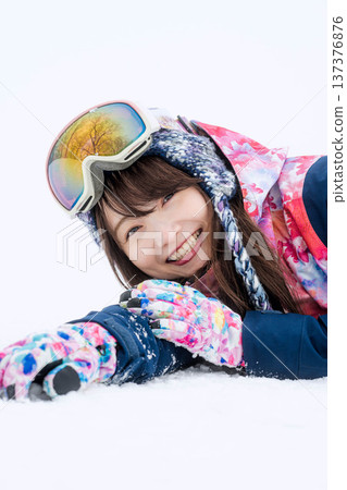 A young woman wearing ski wear playing with snow on the slopes A young woman wearing ski wear playing with snow on the slopes 137376876