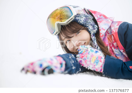 A young woman wearing ski wear playing with snow on the slopes A young woman wearing ski wear playing with snow on the slopes 137376877