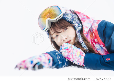 一位身穿滑雪服的年輕女子在雪坡上玩雪。 137376882