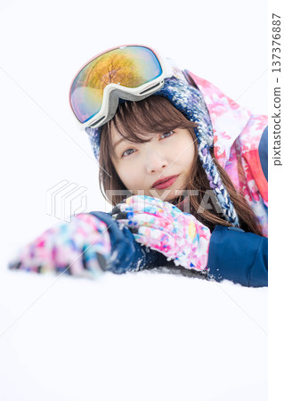 一位身穿滑雪服的年輕女子在雪坡上玩雪。 137376887