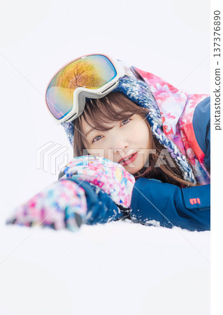 一位身穿滑雪服的年輕女子在雪坡上玩雪。 137376890