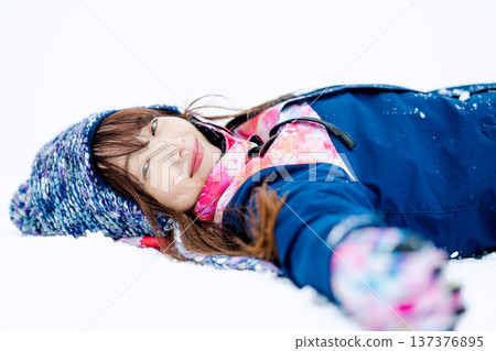 一位身穿滑雪服的年輕女子在雪坡上玩雪。 137376895