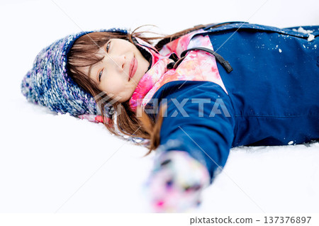一位身穿滑雪服的年輕女子在雪坡上玩雪。 一位身穿滑雪服的年輕女子在雪坡上玩雪。 137376897
