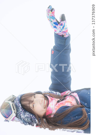 一位身穿滑雪服的年輕女子在雪坡上玩雪。 137376909