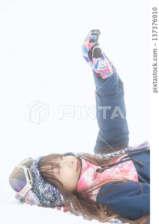 一位身穿滑雪服的年輕女子在雪坡上玩雪。 137376910