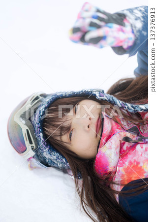 一位身穿滑雪服的年輕女子在雪坡上玩雪。 一位身穿滑雪服的年輕女子在雪坡上玩雪。 137376913