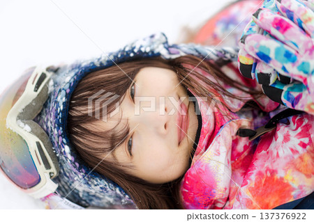 A young woman wearing ski wear playing with snow on the slopes A young woman wearing ski wear playing with snow on the slopes 137376922