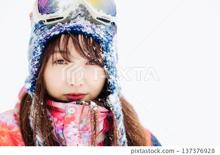 一位身穿滑雪服的年輕女子在雪坡上玩雪。 一位身穿滑雪服的年輕女子在雪坡上玩雪。 137376928