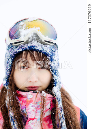一位身穿滑雪服的年輕女子在雪坡上玩雪。 一位身穿滑雪服的年輕女子在雪坡上玩雪。 137376929