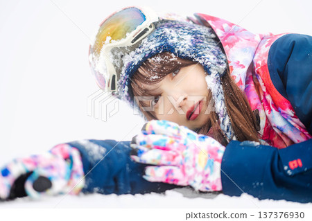 A young woman wearing ski wear playing with snow on the slopes A young woman wearing ski wear playing with snow on the slopes 137376930