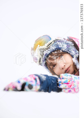 一位身穿滑雪服的年輕女子在雪坡上玩雪。 137376933