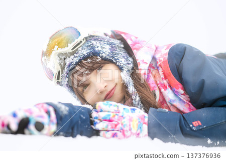 一位身穿滑雪服的年輕女子在雪坡上玩雪。 137376936