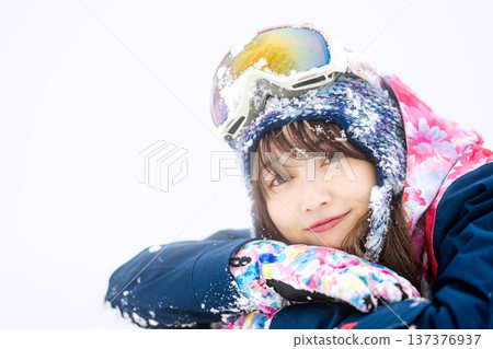 A young woman wearing ski wear playing with snow on the slopes A young woman wearing ski wear playing with snow on the slopes 137376937