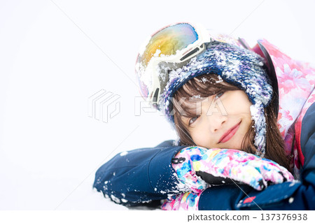 一位身穿滑雪服的年輕女子在雪坡上玩雪。 137376938