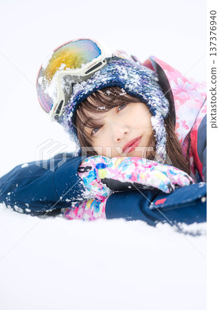 一位身穿滑雪服的年輕女子在雪坡上玩雪。 137376940