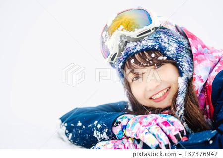 一位身穿滑雪服的年輕女子在雪坡上玩雪。 一位身穿滑雪服的年輕女子在雪坡上玩雪。 137376942