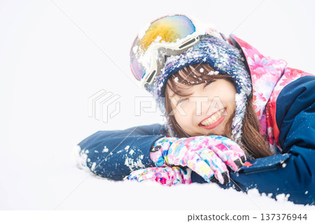 一位身穿滑雪服的年輕女子在雪坡上玩雪。 137376944