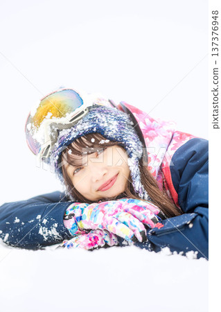 一位身穿滑雪服的年輕女子在雪坡上玩雪。 一位身穿滑雪服的年輕女子在雪坡上玩雪。 137376948