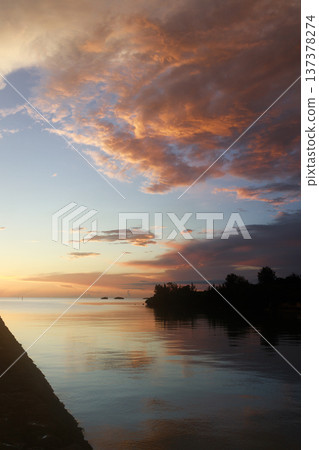 夕陽西下,雲彩倒映在平靜的海面上。 夕陽西下,雲彩倒映在平靜的海面上。 137378274