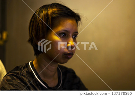 Woman Working At Screen With Light On Face, A focused woman illuminated by screen glow in a dark room, capturing modern work culture, ideal for technology and business advertising. Woman Working At Screen With Light On Face, A focused woman illuminated by screen glow in a dark room, capturing modern work culture, ideal for technology and business advertising. 137378590