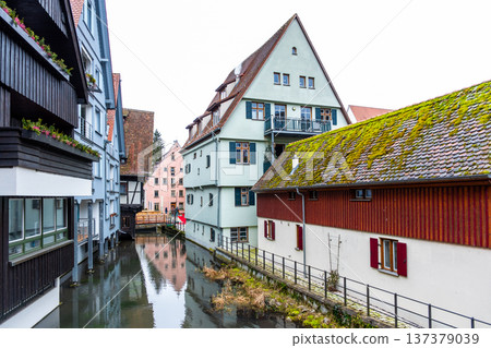 A tranquil canal in the fishermans quarter of Ulm, Germany. Reflections of colorful buildings line the water edge, creating a serene urban scene. A tranquil canal in the fishermans quarter of Ulm, Germany. Reflections of colorful buildings line the water edge, creating a serene urban scene. 137379039